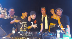 DJ Dominick omringd door andere leden van het Jazz Circus Collective, waaronder DJ Cassie 6, percussionist Koen van den Broek en zangeres Juliet July.