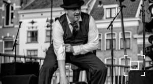 DJ Dominick met bolhoed als jazz MC tijdens een buiten optreden.